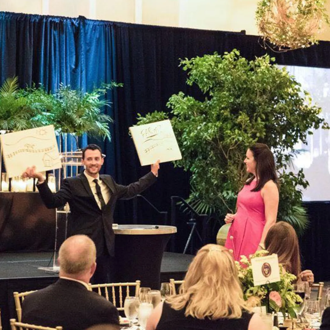 Josh Fletcher performing a mentalist act at an event, holding up drawings.